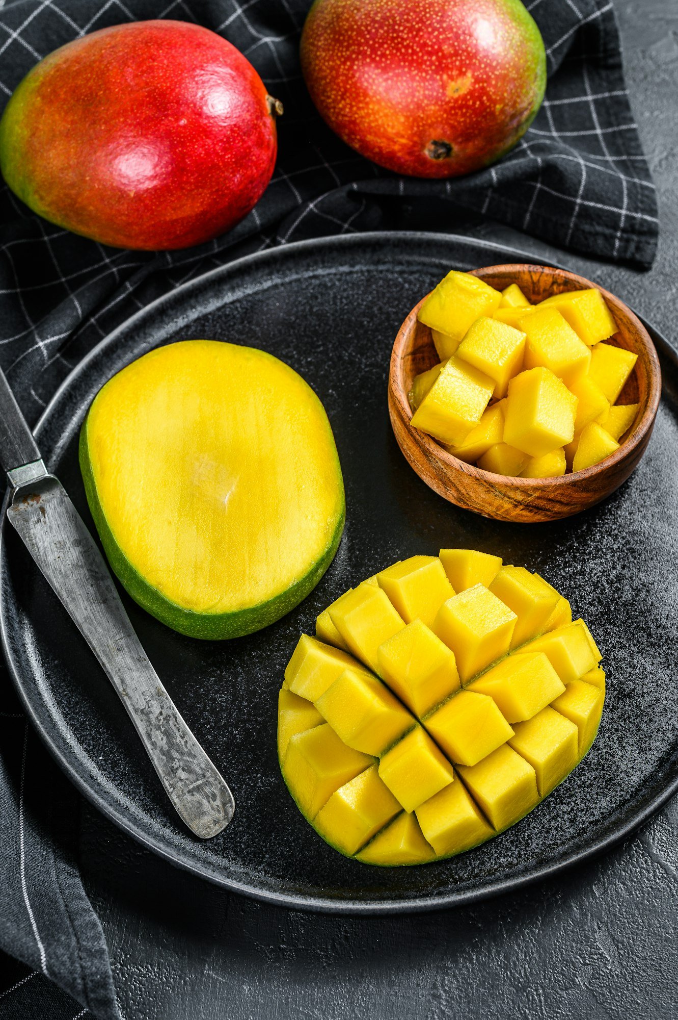 A ripe mango. Cut into cubes tropical fruit. Black background. Top view